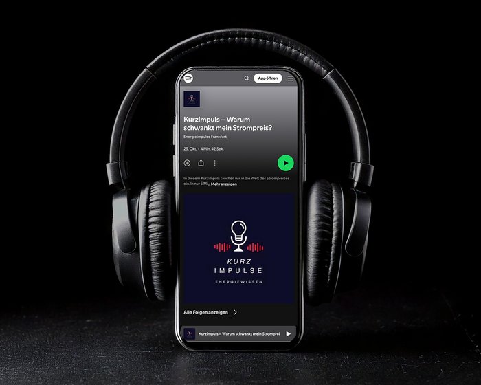 Ein Bild eines schwarzen Smartphones, das eine Podcast-Episode namens „Kurzimpuls – Warum schwankt mein Strompreis?“ zeigt, umgeben von einem schwarzen Kopfhörer, platziert auf einem stilvollen, schwarzen Hintergrund.