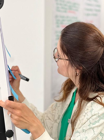 Seitenansischt einer Frau, die etwas auf ein Whiteboard schreibt