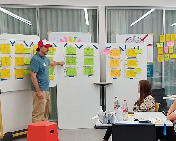 Lars Michaelis erklärt verschiedene Skizzen an einem Whiteboard vor einer Gruppe.